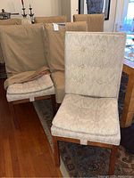 Six matching chairs, some with slipcovers on, some removed, arranged on floor