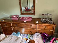 Front view of the triple dresser with bamboo style accents, six drawers with ring pulls, mirror above, and items on top.