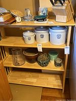 Full view of the wooden folding shelf with three tiers shown with various items on the shelves to illustrate size, items not included.