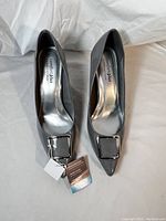 Pair of new gray patent women's pumps with square faux buckles, size 9, photographed from above showing tags and interior brand label.