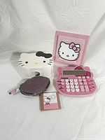 Lot laid out showing all included items: rhinestone Hello Kitty desk calculator, white tape dispenser, memo holder, glittery purple pouch with pen, and sticky notes.