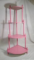 Full view of the pink four-tier corner shelf showing its overall structure and design.