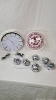 Photo showing wall clock, small pillow, and Christmas silver jingle bells door hanger together.