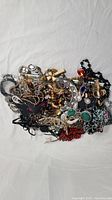 Overhead view of a pile of assorted vintage and modern costume jewelry displayed on a white fabric background.