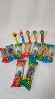 Lot of 14 vintage PEZ candy dispensers arranged in two rows on a white background, featuring colorful character heads including Woody Woodpecker, Kermit, and Star Wars droids.