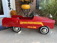 Side view of red metal pedal car with ‘FIRE FIGHTER unit no. 508’ decal