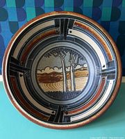 Top view showing full interior of large pottery bowl with landscape and geometric pattern.