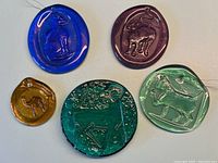 Five Blenko glass pieces on white background showing colors and animal impressions