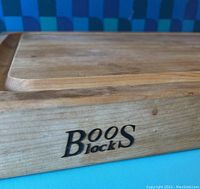 Close-up of the Boos Block brand logo on the side edge of the thick wood cutting board.