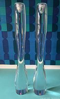 Both candlesticks side by side on blue surface against patterned backdrop