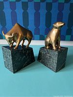 Pair of brass bookends with bull and bear figures on dark green marble bases, front angle