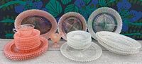Overview of the pink and clear depression glass lot including several plates, bowls, cups and a divided serving platter.