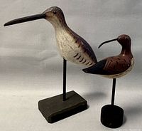 View of both carved wooden bird sculptures displayed side by side showing relative size and details.