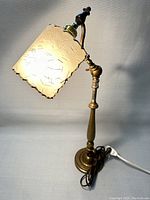 Full view of the vintage industrial style desk lamp illuminated, showing the brass body and fibreglass retro shade with decorative lines.