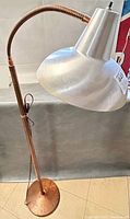Full view of vintage industrial floor lamp with copper adjustable arm and large steel shade.