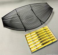 Set of 6 English dessert knives with white handles in a yellow box next to black wired tray.