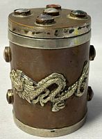 Front and side views of the cylindrical antique copper box showing embossed silver dragon and agate gemstones on lid and sides.