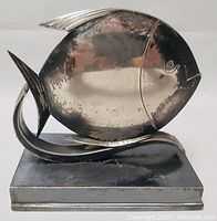 Front view of silver plate fish sculpture showing rounded body and metal base