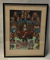 Full view of the framed Tibetan Thangka painting showing multiple traditional figures and the frame condition.