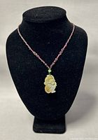 Full view of the jade monkey pendant necklace displayed on a black velvet bust.