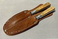 Brown leather holster with stitched edges and metal rivets suitable for holding the carving set.