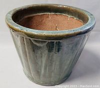 Front view showing the green glazed exterior with vertical ridges and large opening.