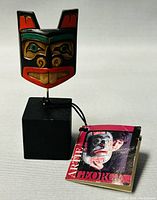 Front view of hand painted wood carving with attached booklet showing the artist's photo and name.