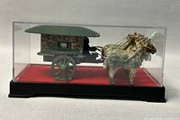 Front view of the vintage Chinese model horse-drawn carriage in a clear rectangular display case showing two white horses with gold harnesses and the green-carriage body.