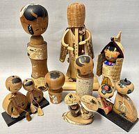 Photo shows full set of 11 vintage Japanese Kokeshi wood dolls in varied styles, sizes, and decorations arranged together on flat surface.
