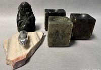 Lot overview showing all carved pieces including the signed aluminum wolf figurine, Inuit soapstone figure, and the three carved soapstone cube blocks on a light background.