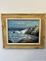 Front facing full view of the framed landscape painting showing the sea cove and waves with rustic wood frame.