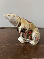 Side angle of the seated polar bear porcelain figurine showing detailed Imari pattern and gold gilding on the body.