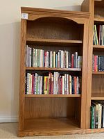Front view of solid wood bookcase filled partially with cookbooks on two middle shelves