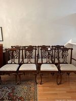 Eight chairs lined up against a wall on hardwood floor.