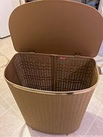 Top view of brown plastic laundry hamper with hinged lid, showing interior and texture