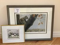 Overview showing both framed prints: large grey-framed squirrel print and smaller gold-tone framed farmhouse print