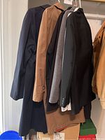 Side view showing multiple jackets hanging including black tuxedo, brown and blue jackets.