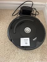 Top view of black iRobot Roomba robot vacuum with central 'Clean' button and MaxSold sticker.