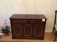 Solid wooden sideboard front view showing four drawers and three doors with metal handles.