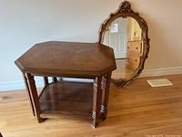 Full view of the solid wood octagonal end table showing the table top, fluted legs, and lower shelf. Some wear and scratches visible.