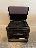 Front view of the Sharp compact disc stereo system with open CD player lid, front cassette deck visible, and control buttons on the front panel.