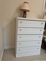 Full view of white five-drawer dresser with lamp on top showing the item set.