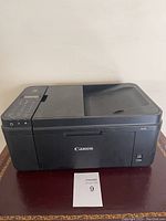 Front view of one Canon multifunction printer showing control panel, scanner lid, and paper input tray.