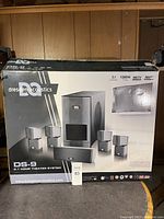 Box of Dresden Acoustics DS-9 home theater system showing main image of speakers and subwoofer with product information and branding.