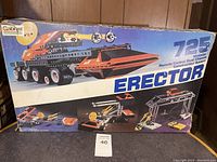 Box front of Erector 725 set showing motorized remote control dual chassis construction model with orange and black colors and multiple wheels.