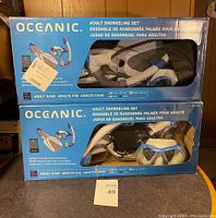 Two boxed Oceanic adult snorkeling sets stacked, showing box front with product image and mesh bag glimpse.