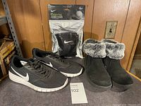 Lot showing black Nike running shoes, black winter boots with fur lining, and Nike knee pads packaged in plastic.