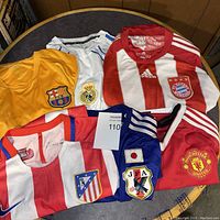 All six soccer jerseys laid out on a table showing distinct club crests and colors.