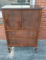 Front view of the dresser showing the upper cabinet doors and two lower drawers with grape vine pull handles.