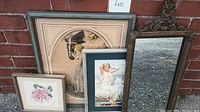 Four items arranged against a brick wall: an antique vanity mirror, two vintage style women portrait prints, and a small framed cut paper rose artwork.